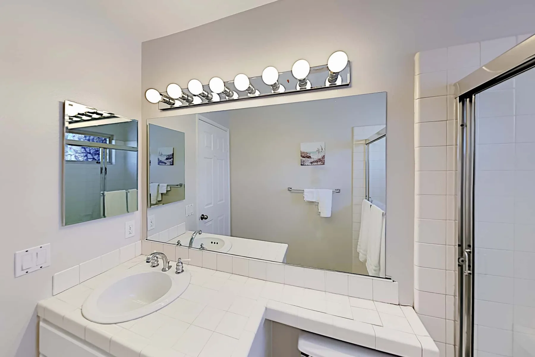 Un tocador de baño con un espejo amplio y un lavabo.