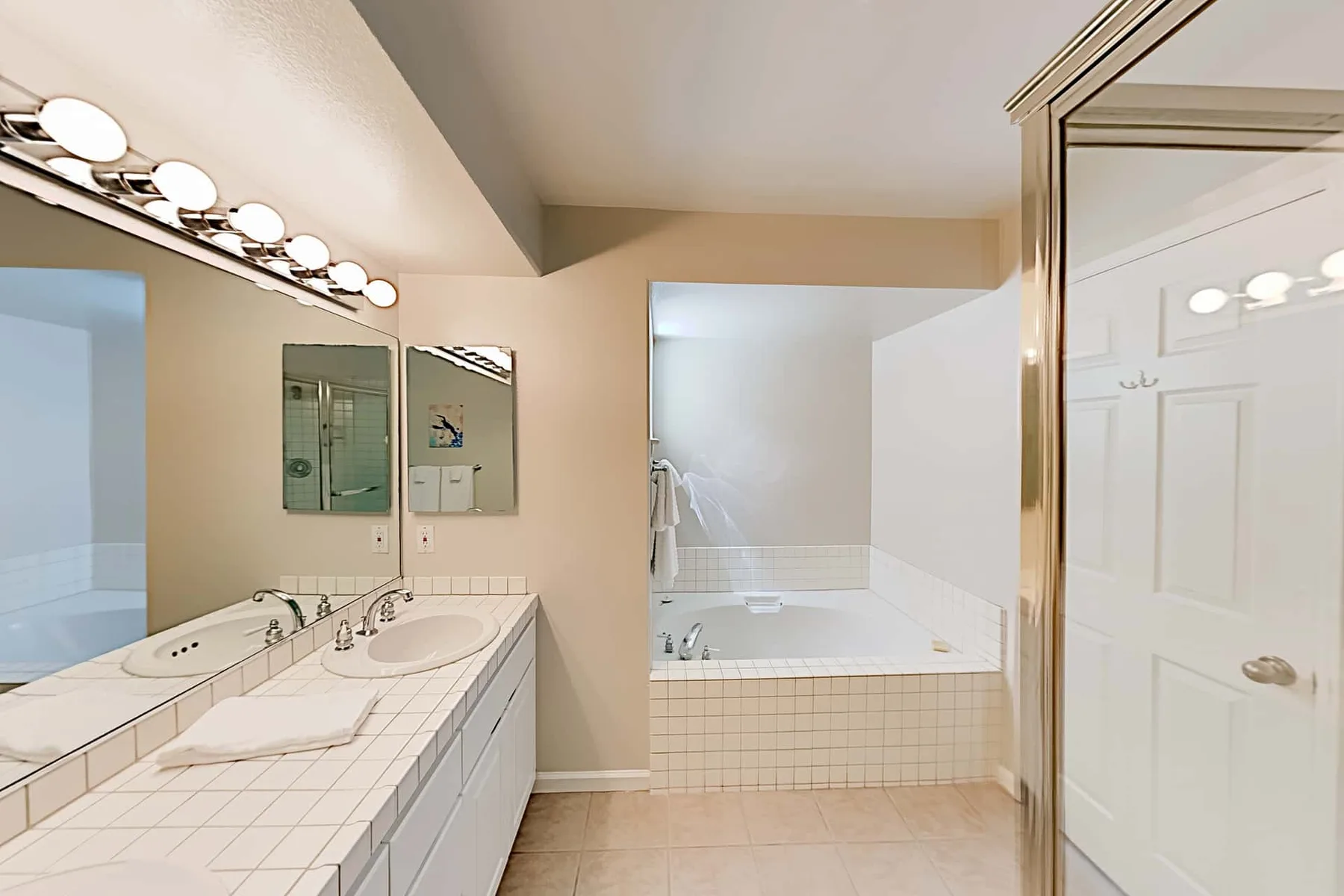 Un baño con un tocador de azulejos y una bañera junto a una ducha de vidrio.