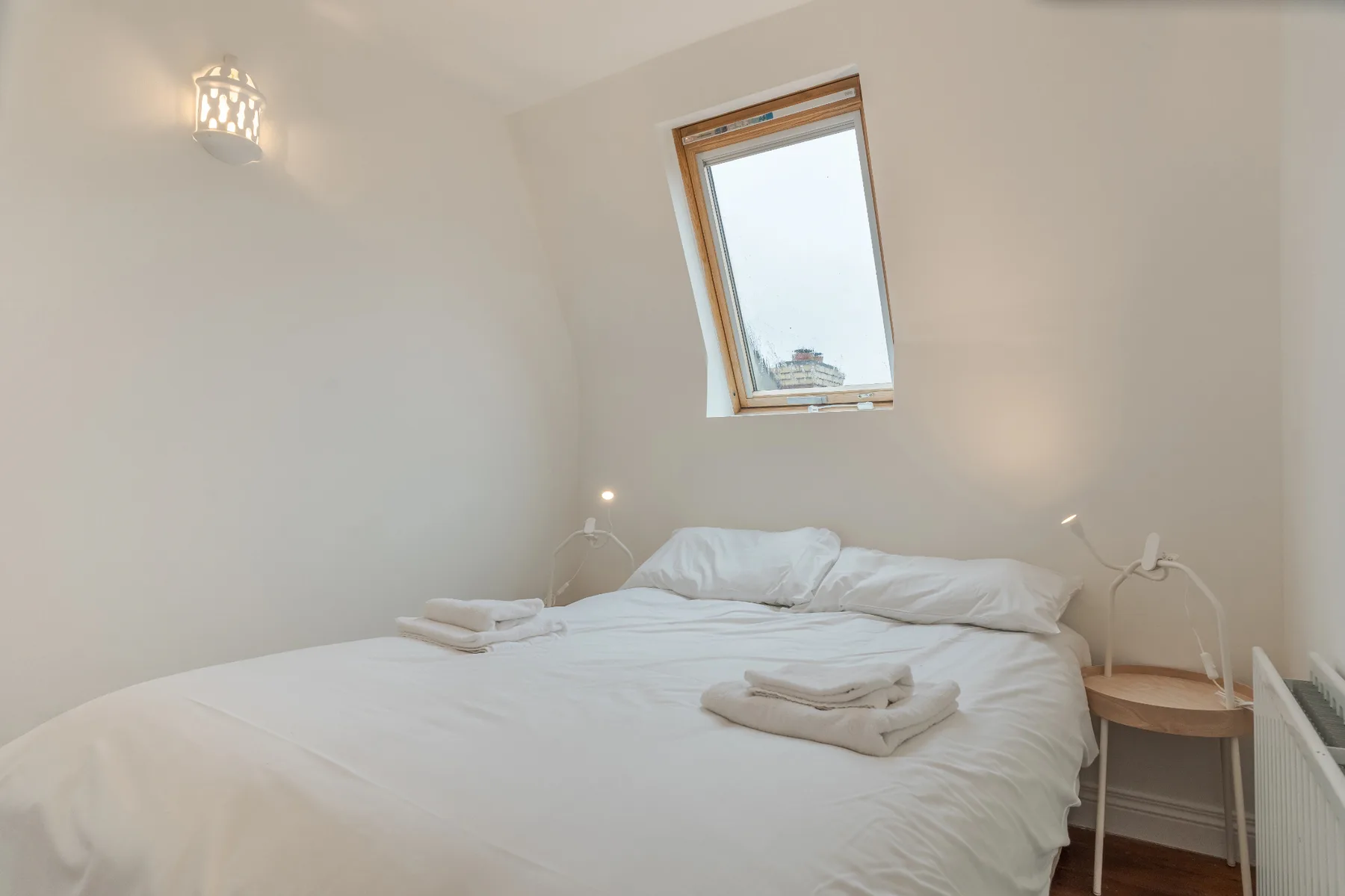 Un dormitorio luminoso con una cama bajo una claraboya inclinada.