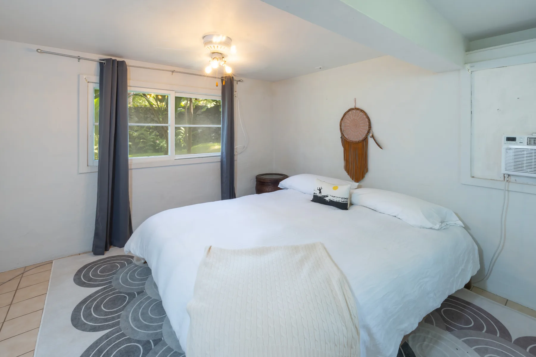 A bedroom with a large bed, windows, and patterned rugs.
