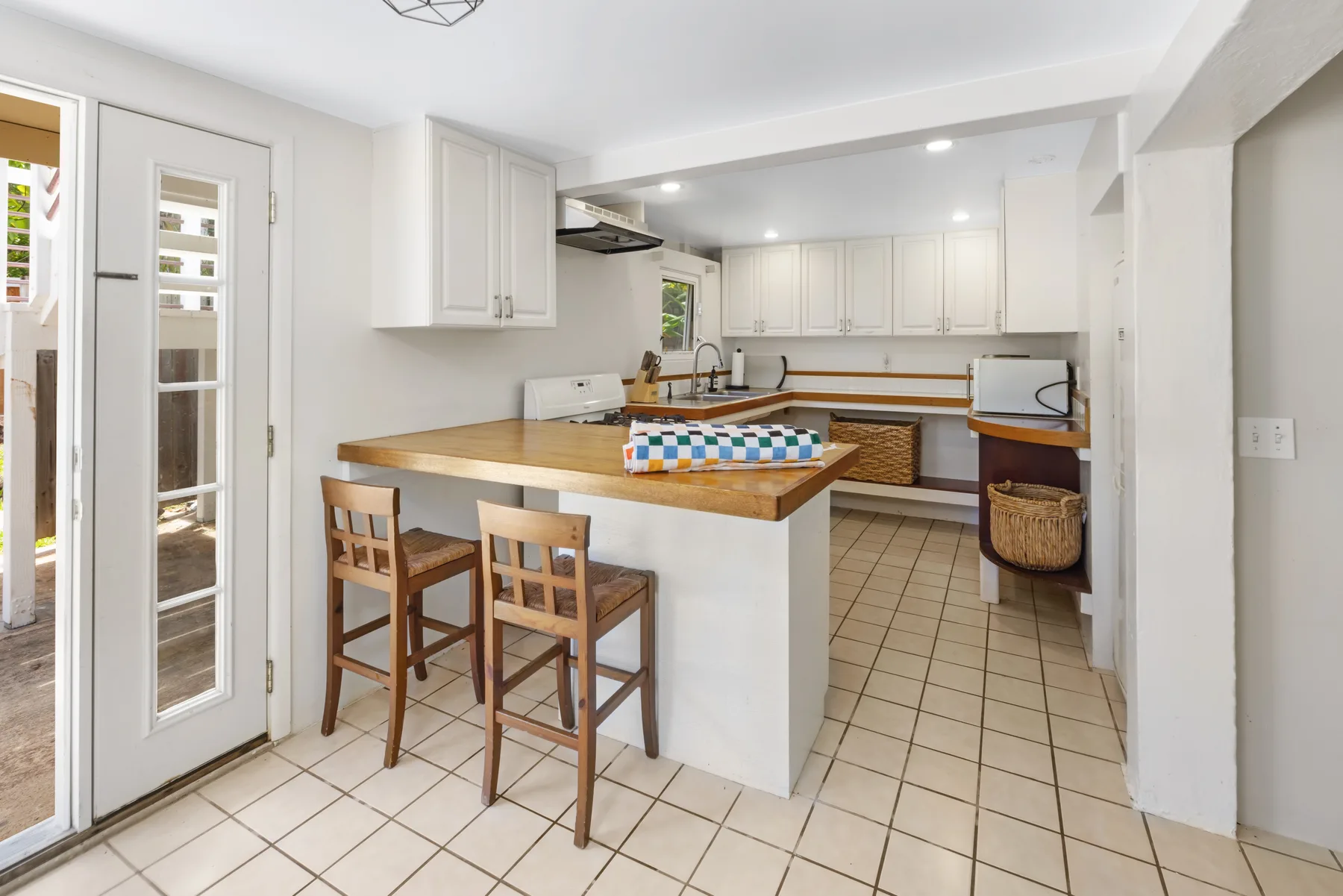 A bright kitchen with a wooden counter and bar stools.