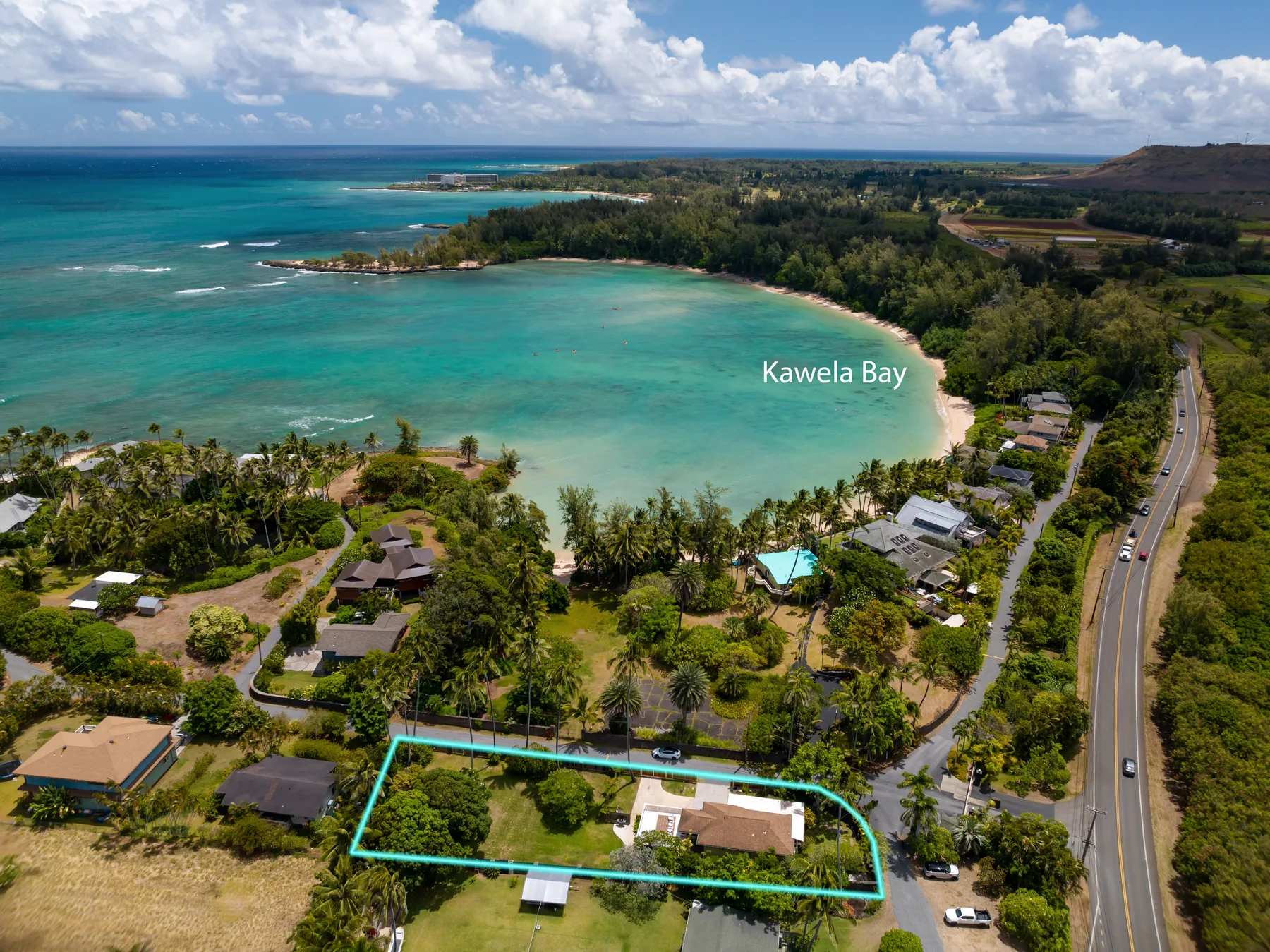 Aerial view of a tropical bay, with turquoise water and a green shoreline.