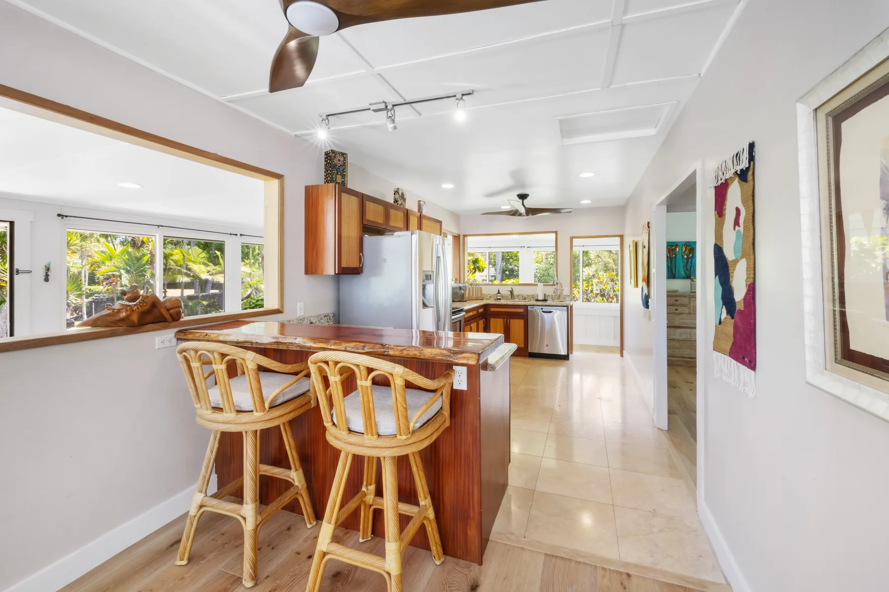 A bright kitchen with a wooden island and seating, opening onto a dining area.