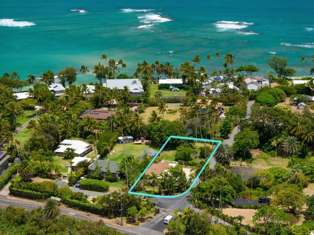 Aerial view of a tropical coastal neighborhood, with a turquoise outline around one property.