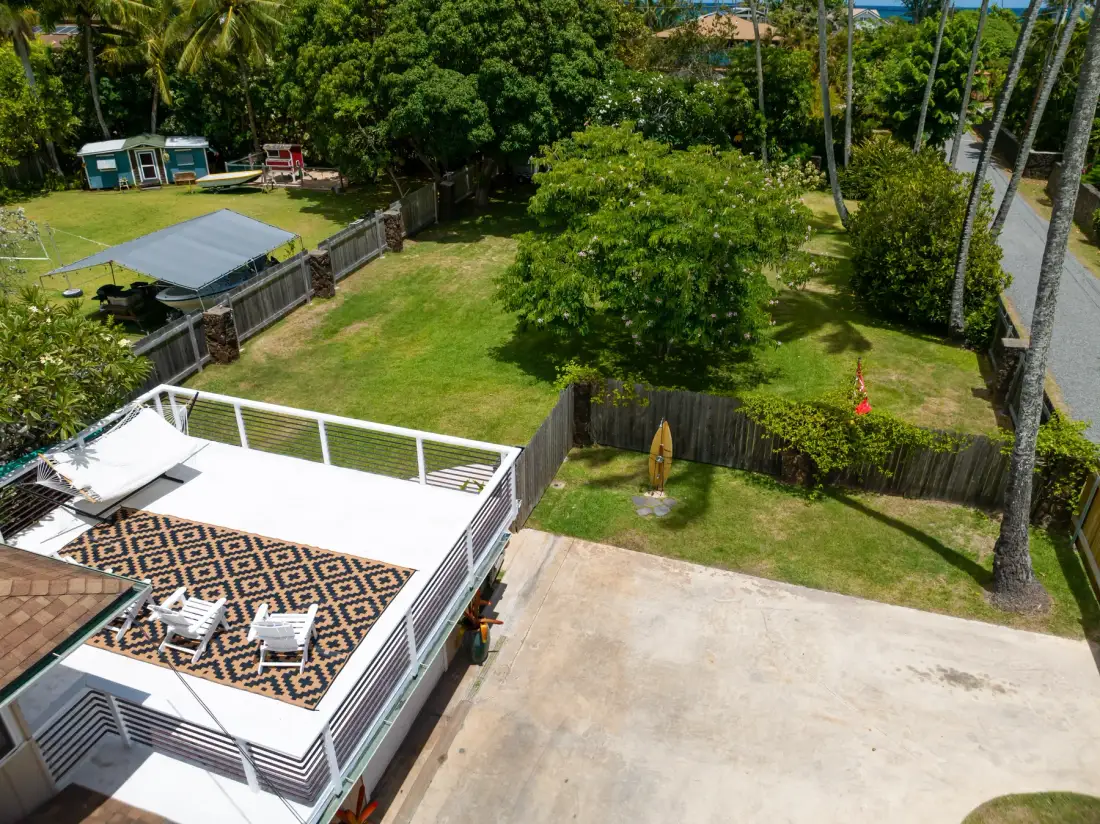 An elevated view of an outdoor deck beside a broad grassy yard.