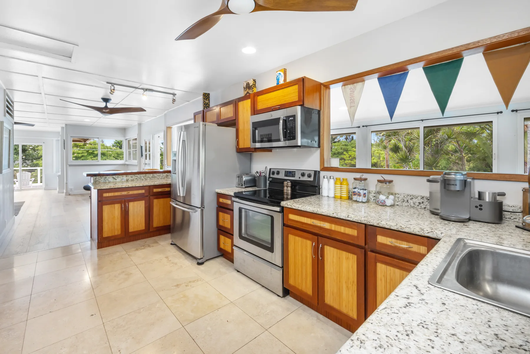 A bright kitchen with wooden cabinets, stainless steel appliances, and a large island.