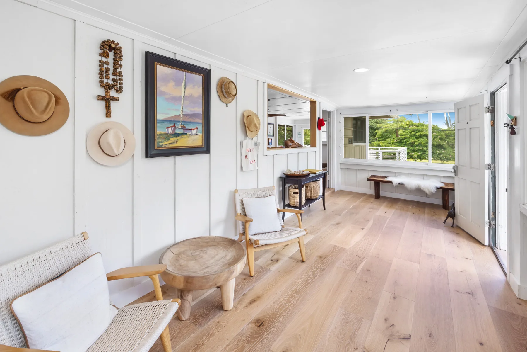 A bright living room with wooden flooring and an open view through the windows.