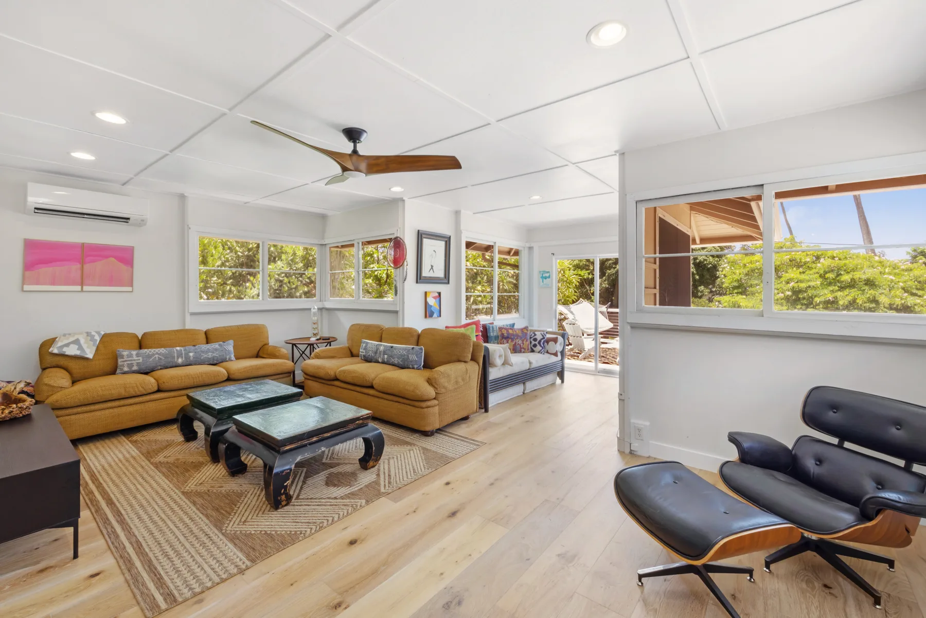 A bright living room with seating arranged around a coffee table and large windows.