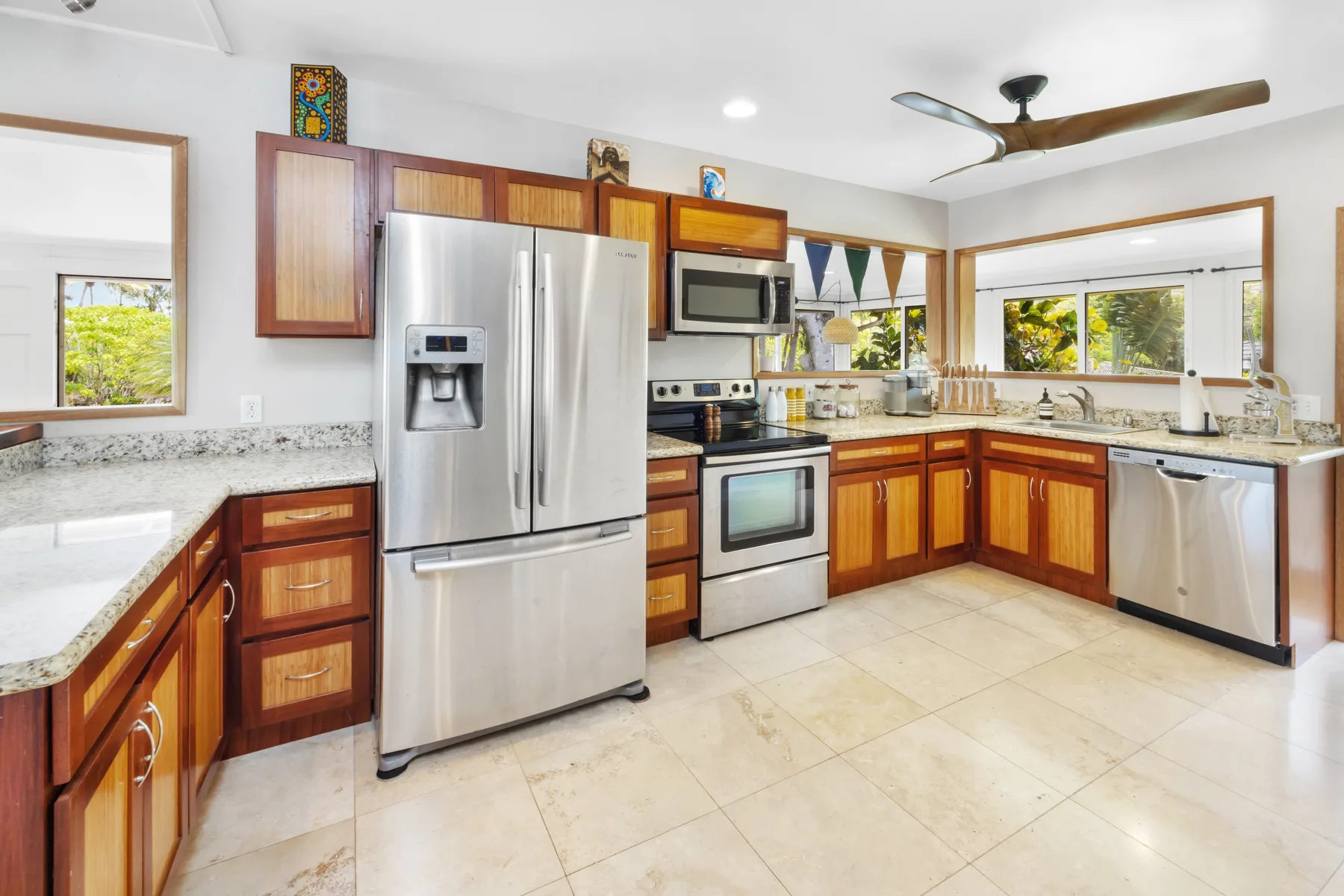 A bright kitchen with wooden cabinets, stainless steel appliances, and wide windows.