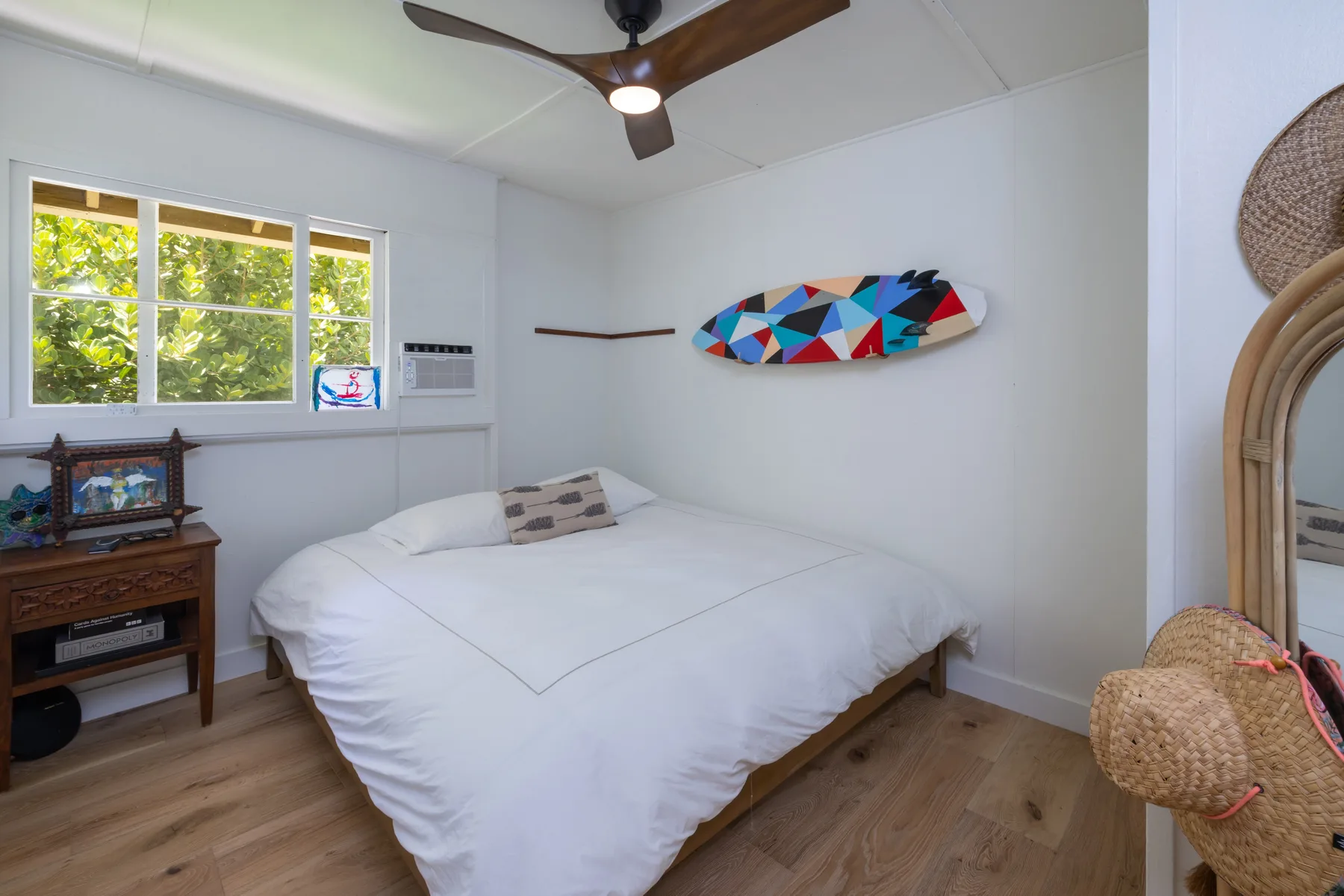 A bedroom with a bed beneath a colorful wall-mounted board.