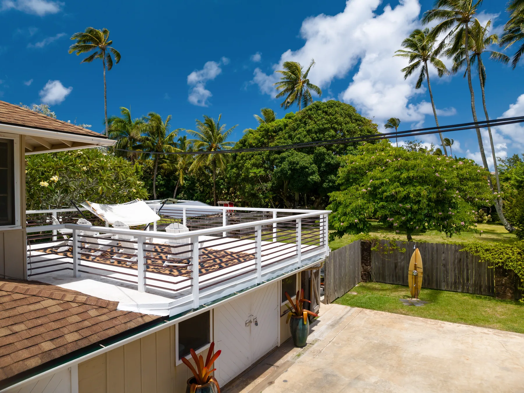 A raised outdoor deck with lounge seating overlooks a tropical garden.