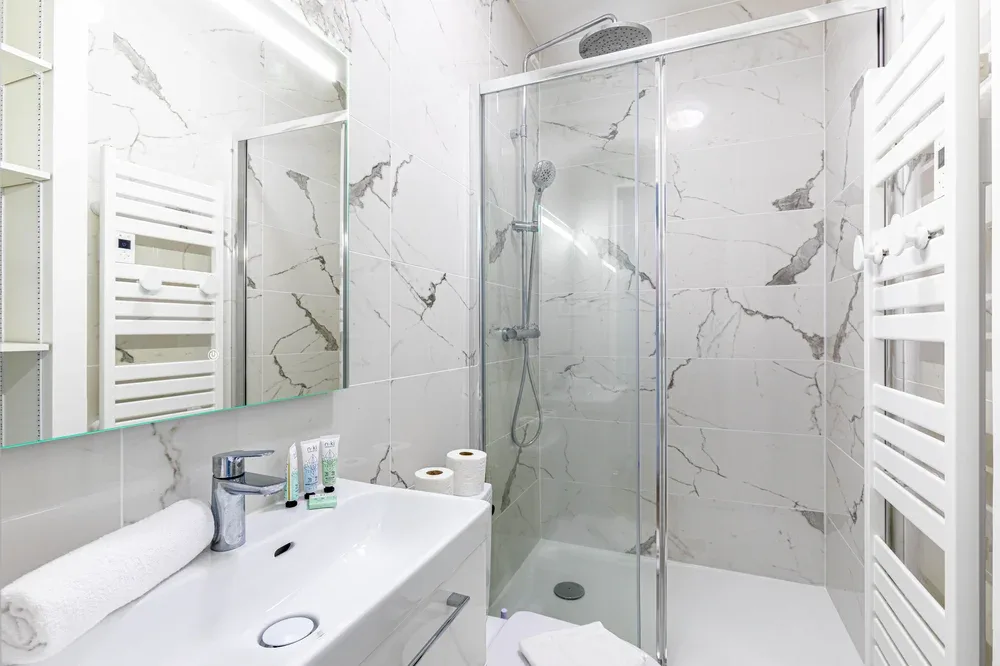 A bright bathroom with a glass shower and a white sink.