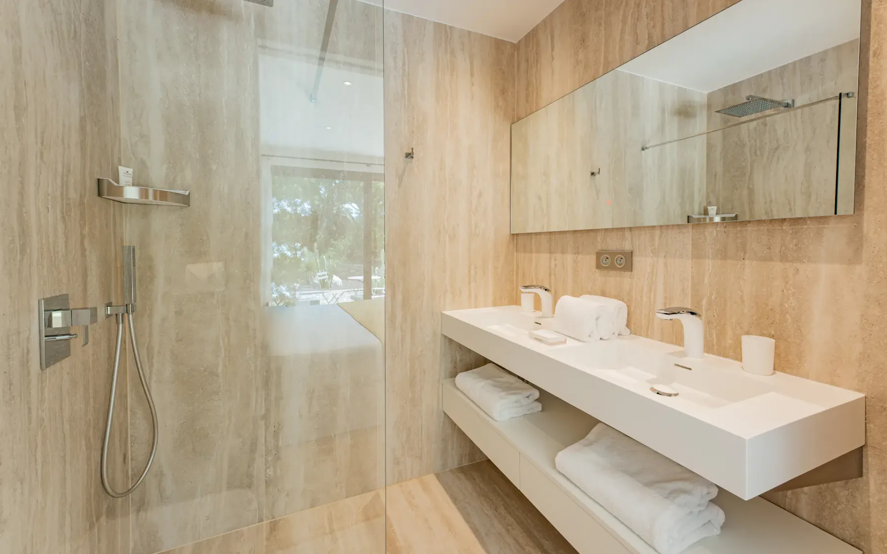 Baño moderno con ducha y una larga encimera blanca con lavabo.