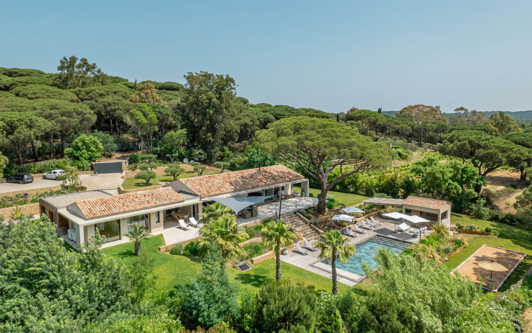 Vista aérea de una villa con piscina entre árboles y vegetación.