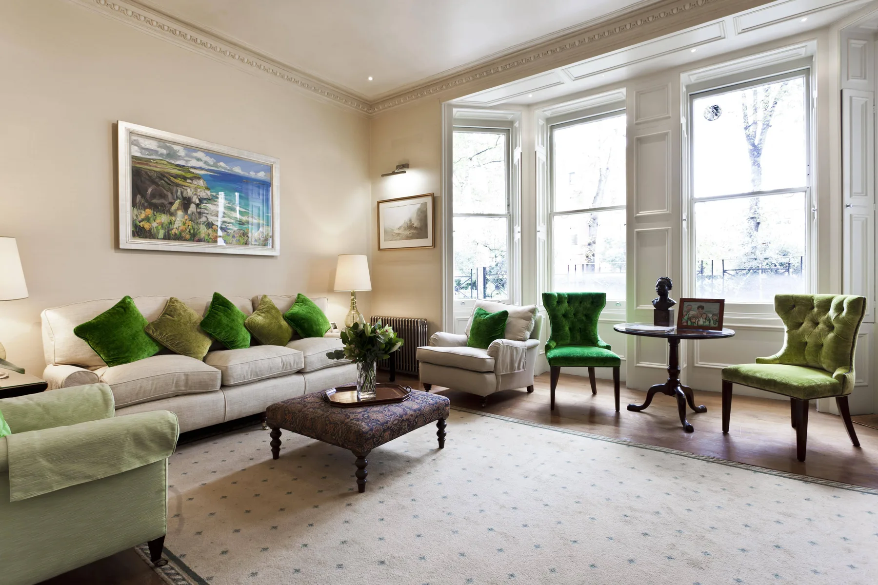 Una sala luminosa con asientos verdes, una mesa de centro y ventanas altas.