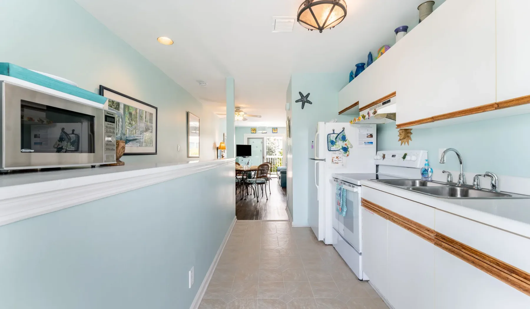 Una cocina luminosa con gabinetes blancos, un refrigerador y una encimera larga.