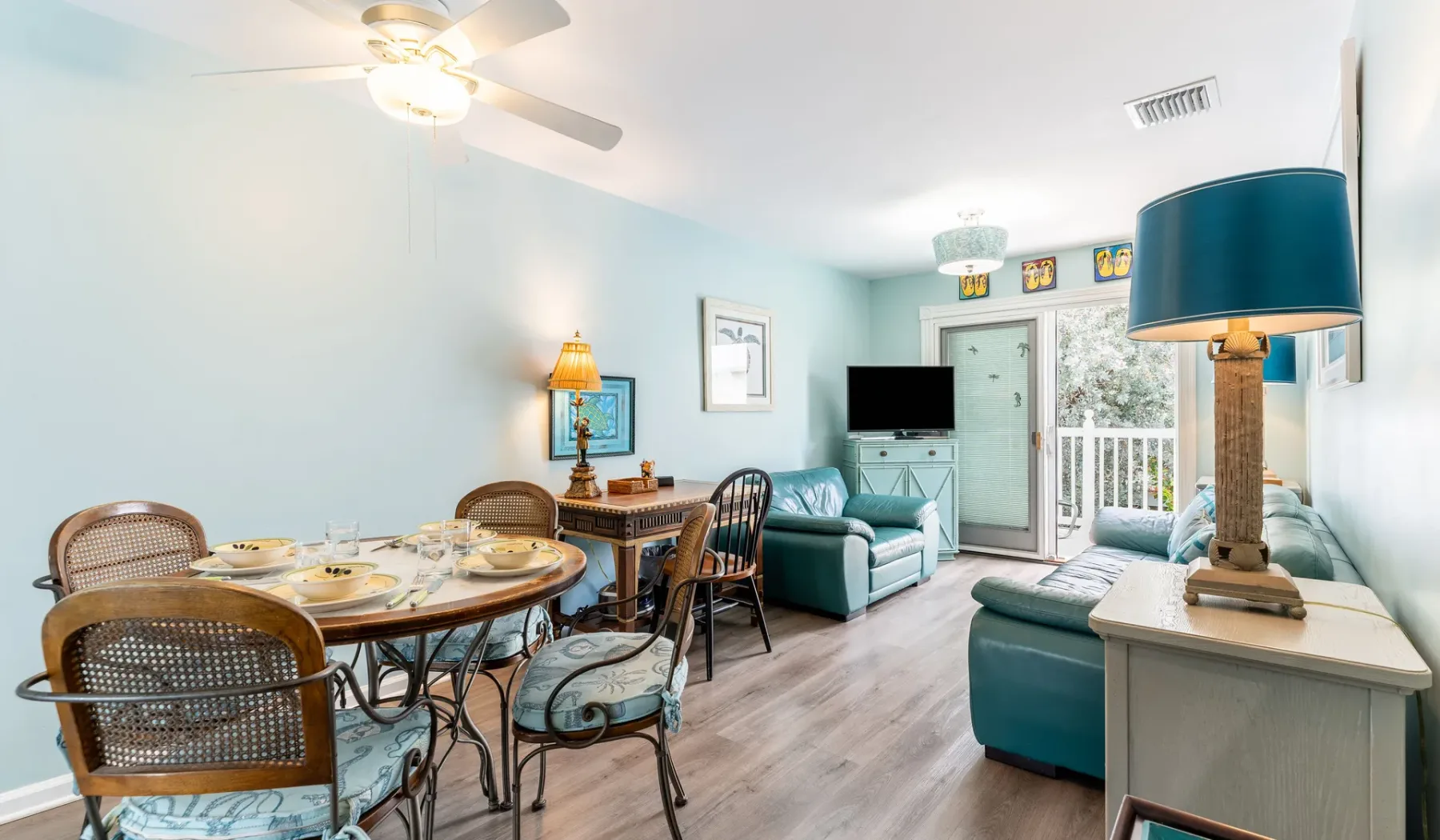 Sala de estar y comedor con una mesa, asientos y puertas de vidrio que dan a un balcón.