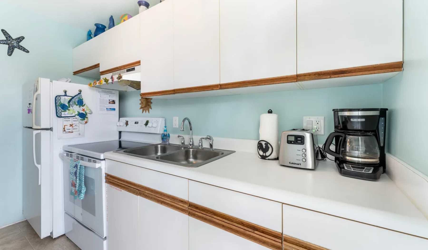 Una cocina luminosa con gabinetes blancos, un fregadero y electrodomésticos sobre la encimera.