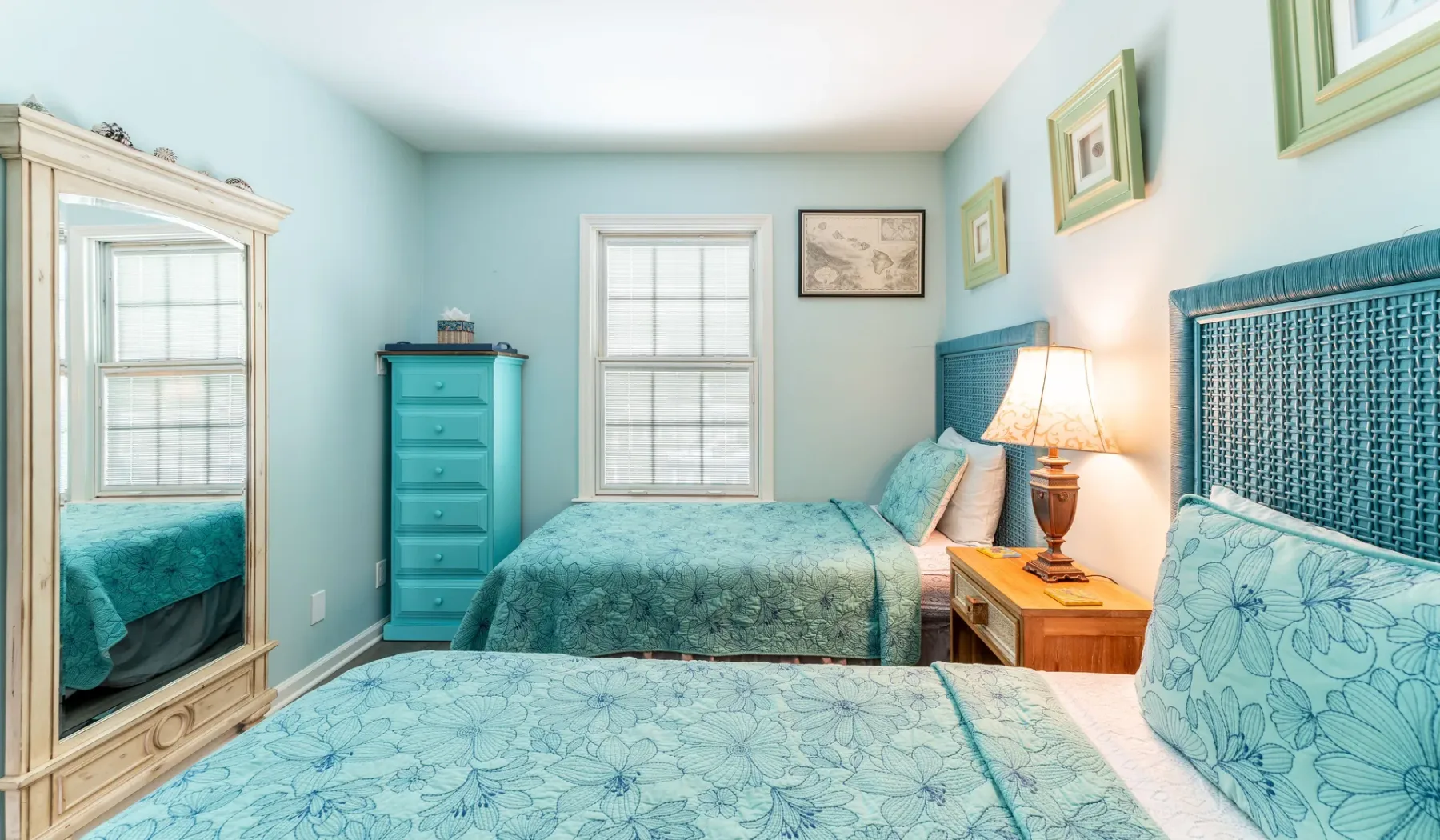 Un dormitorio con ropa de cama verde azulado, un armario con espejo y una lámpara de noche.