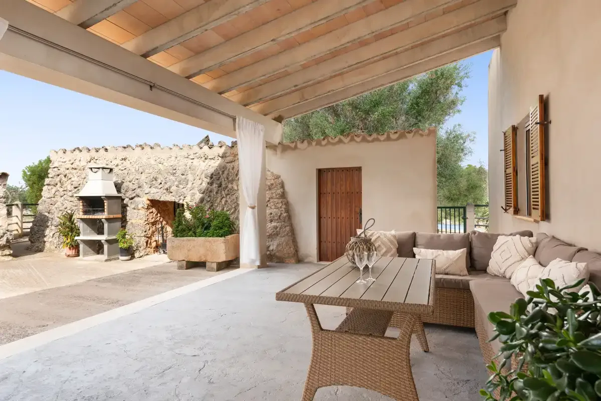 Un patio cubierto con asientos y una vista de una chimenea exterior de piedra.