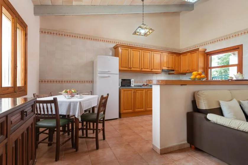 Una cocina y comedor con armarios de madera, una mesa y una zona de estar.