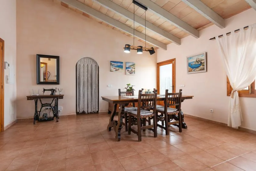 Un comedor con una mesa de madera y sillas bajo vigas expuestas.