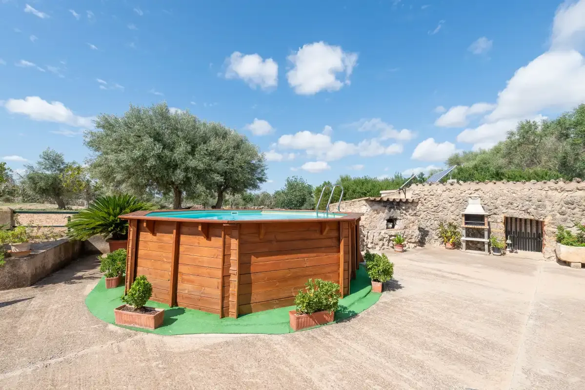 Una piscina al aire libre junto a un muro de piedra y un jardín.