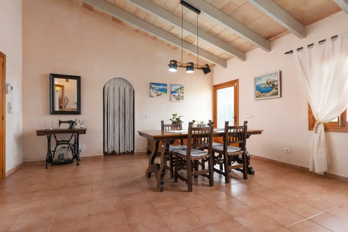 Comedor con una mesa de madera y sillas bajo lámparas colgantes.