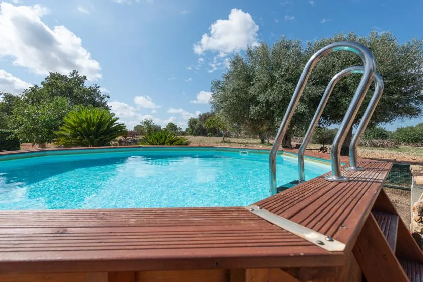 Piscina al aire libre con una terraza de madera y pasamanos metálicos.