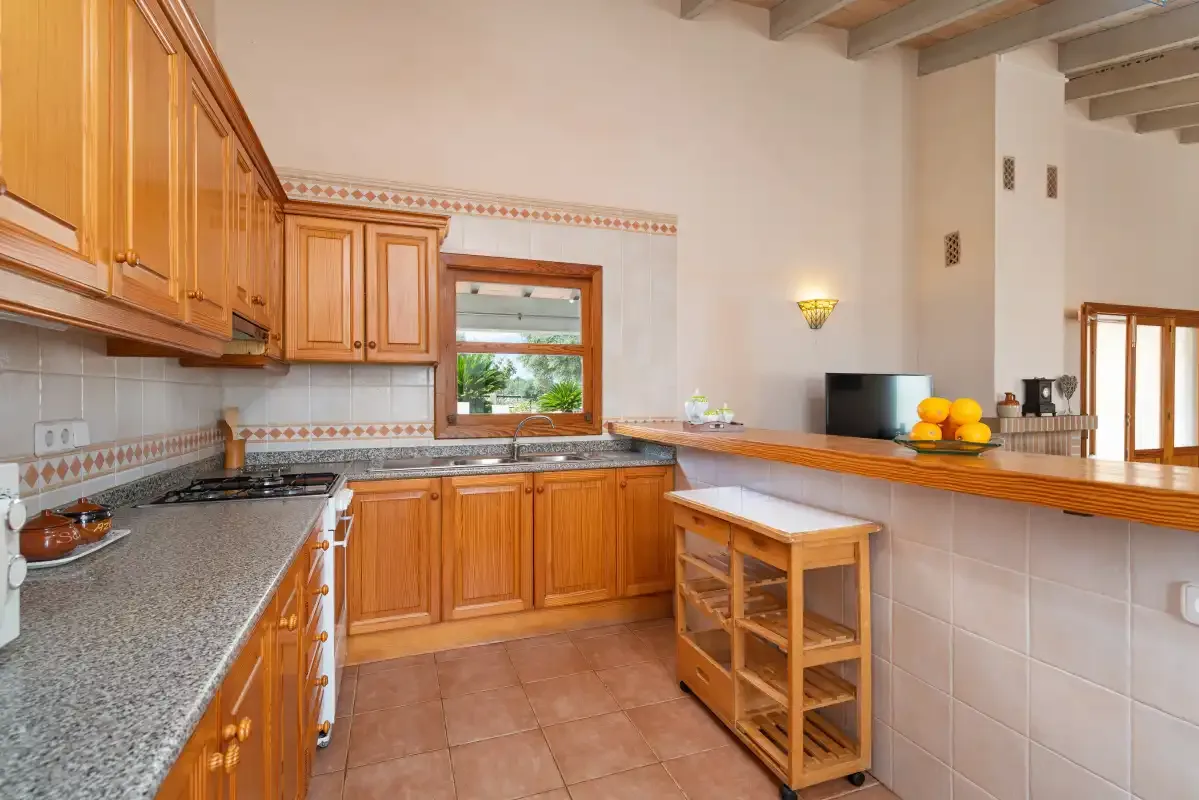 Una cocina con armarios de madera, una encimera y una pequeña isla con ruedas.