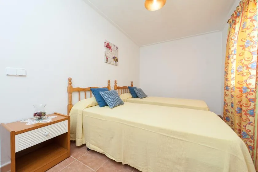 Un dormitorio con dos camas, almohadas azules y cortinas coloridas.