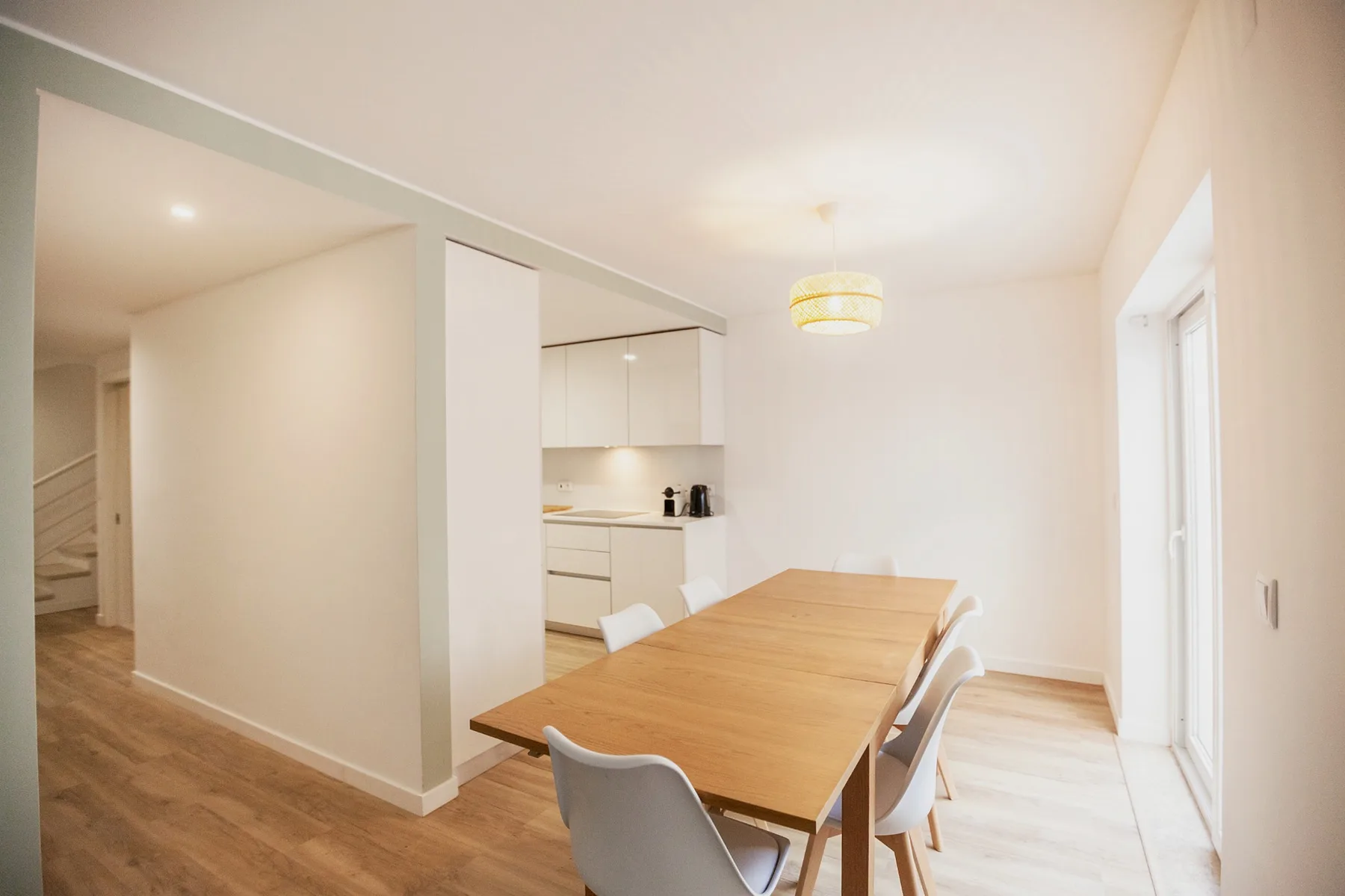 A dining area with a wooden table beside a compact kitchen.