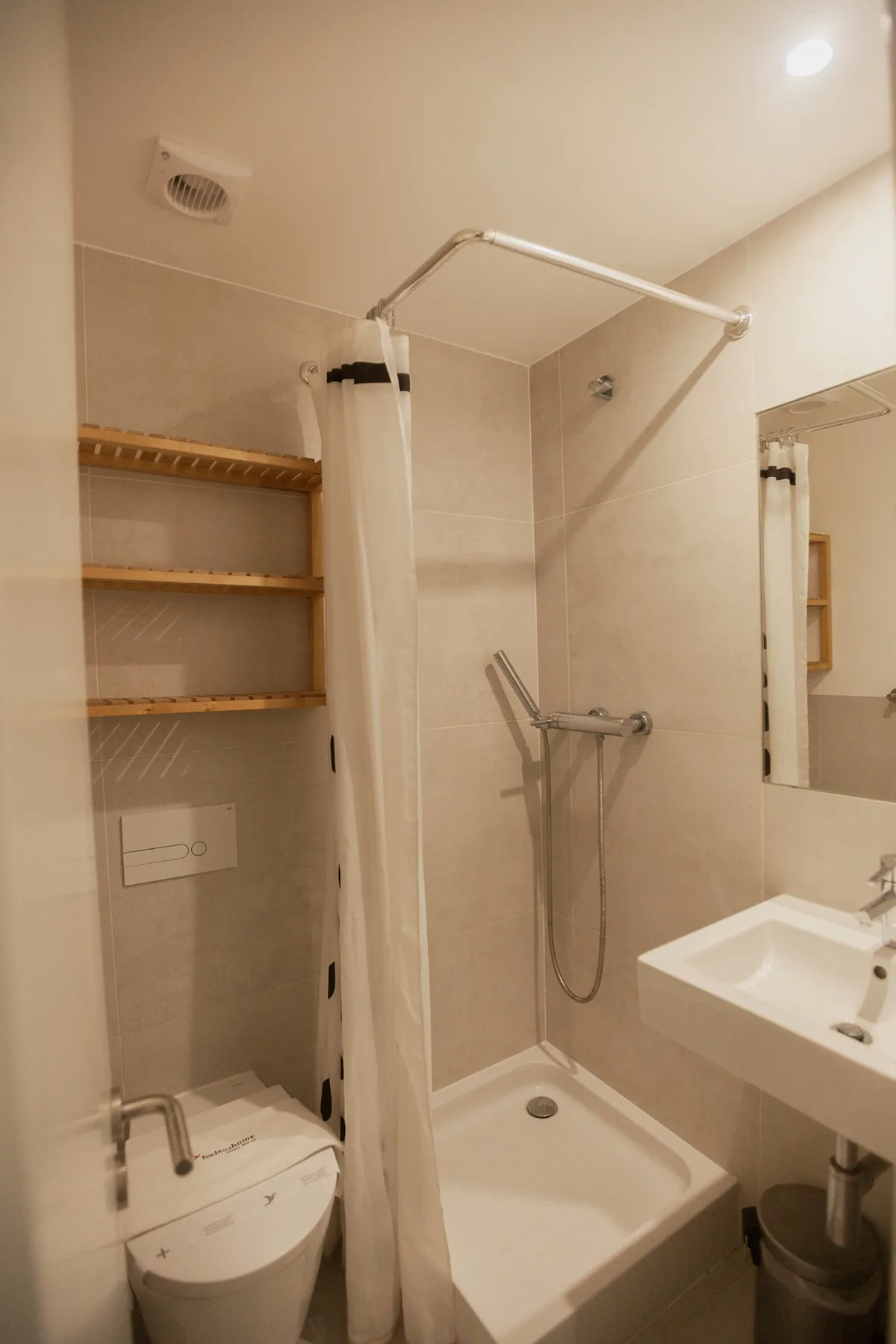A bathroom with a shower, toilet, and wall-mounted sink.