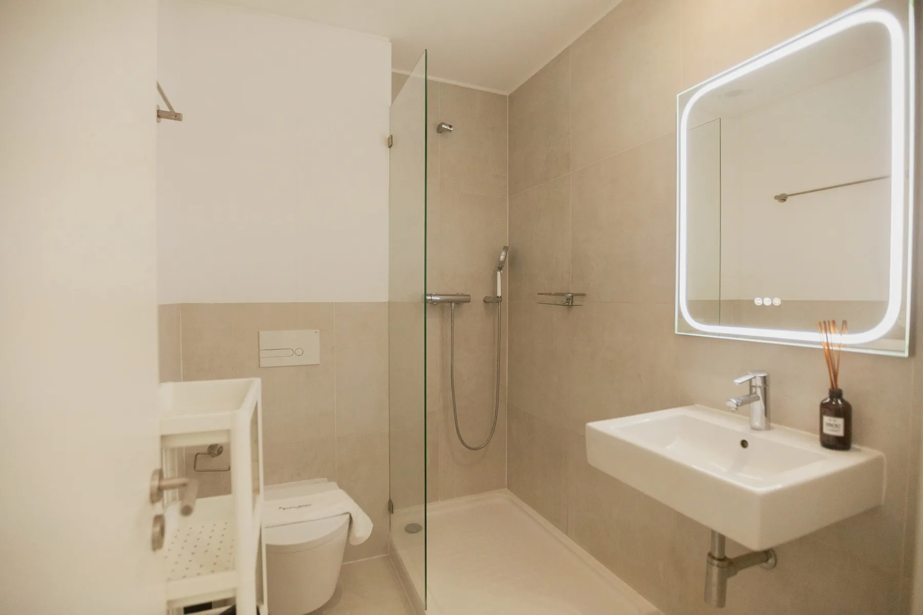 A bathroom with a shower, toilet, and wall-mounted sink.