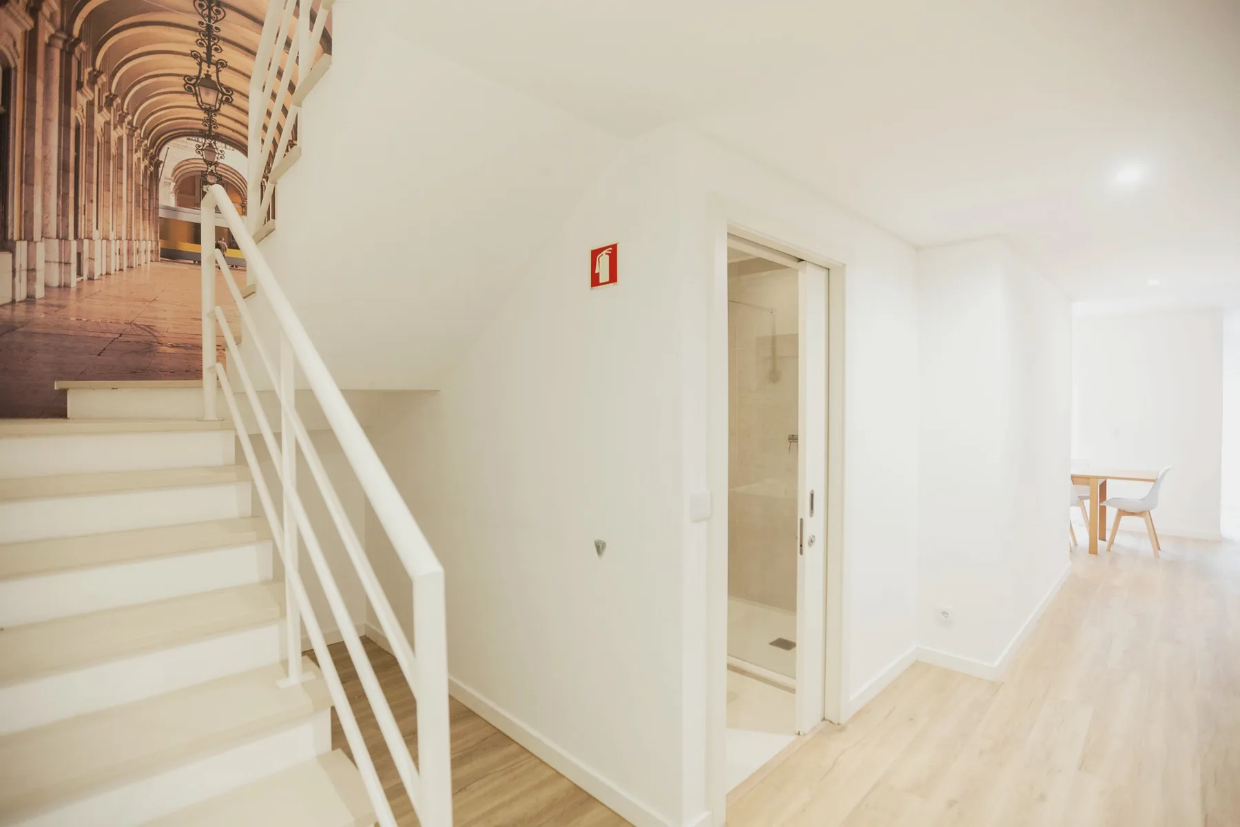 A bright interior hallway with a staircase and an open doorway.