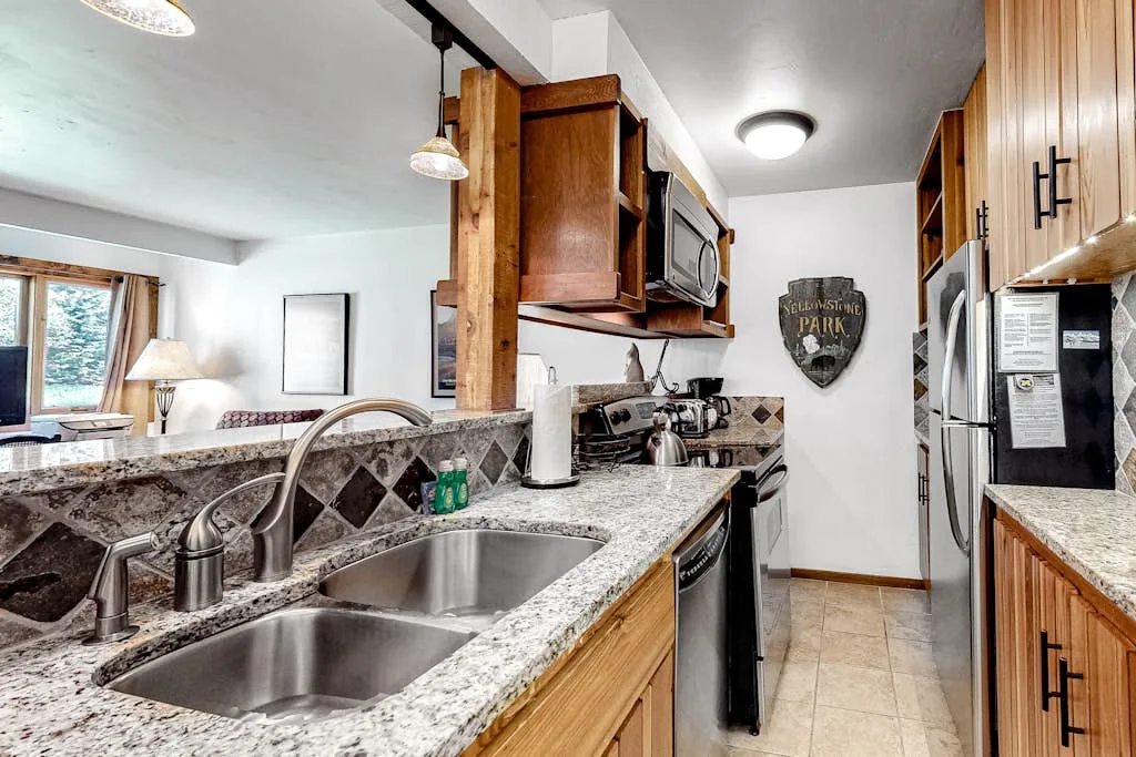 A kitchen with a double sink, wood cabinets, and stainless steel appliances.