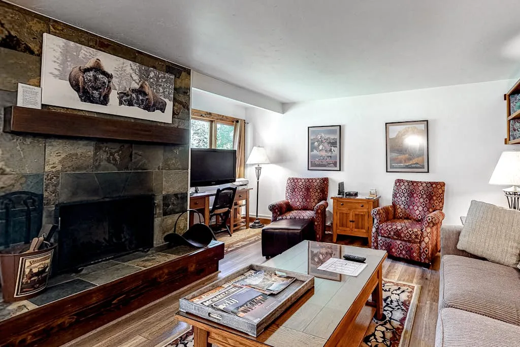 A living room with a stone fireplace, seating, and a coffee table.