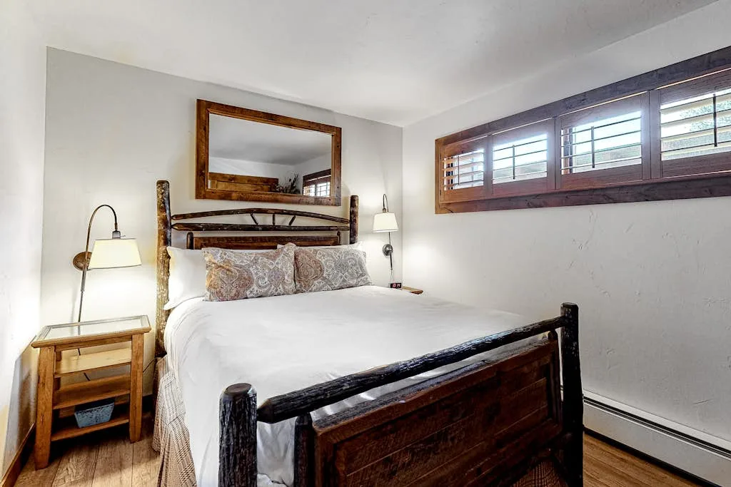 A bedroom with a bed, bedside table, and high horizontal windows.