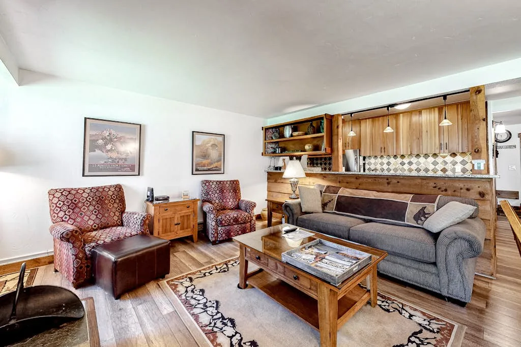 A living room with a gray sofa, patterned armchairs, and a wooden coffee table.
