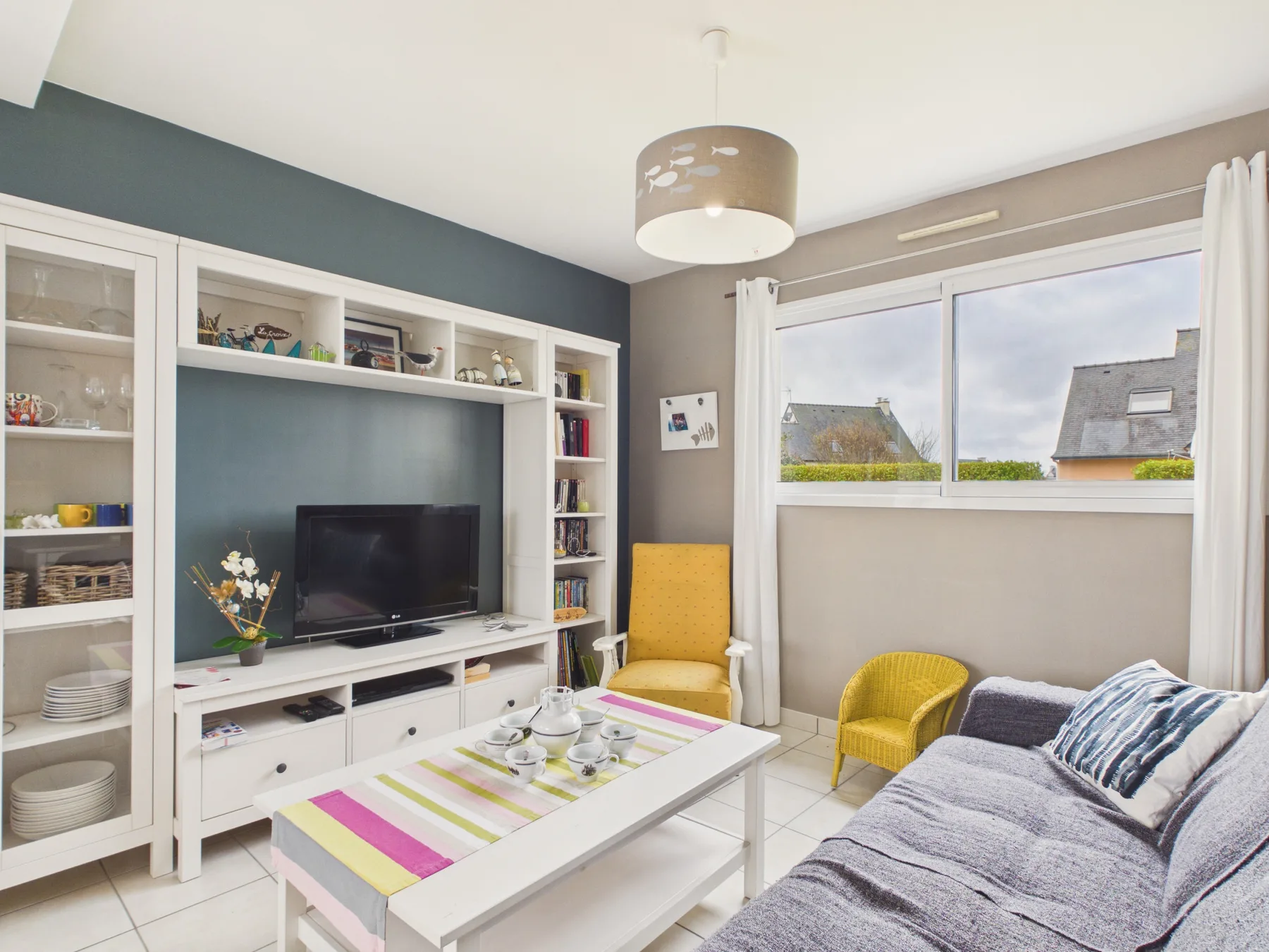 Living room with seating, a television, and a large window.