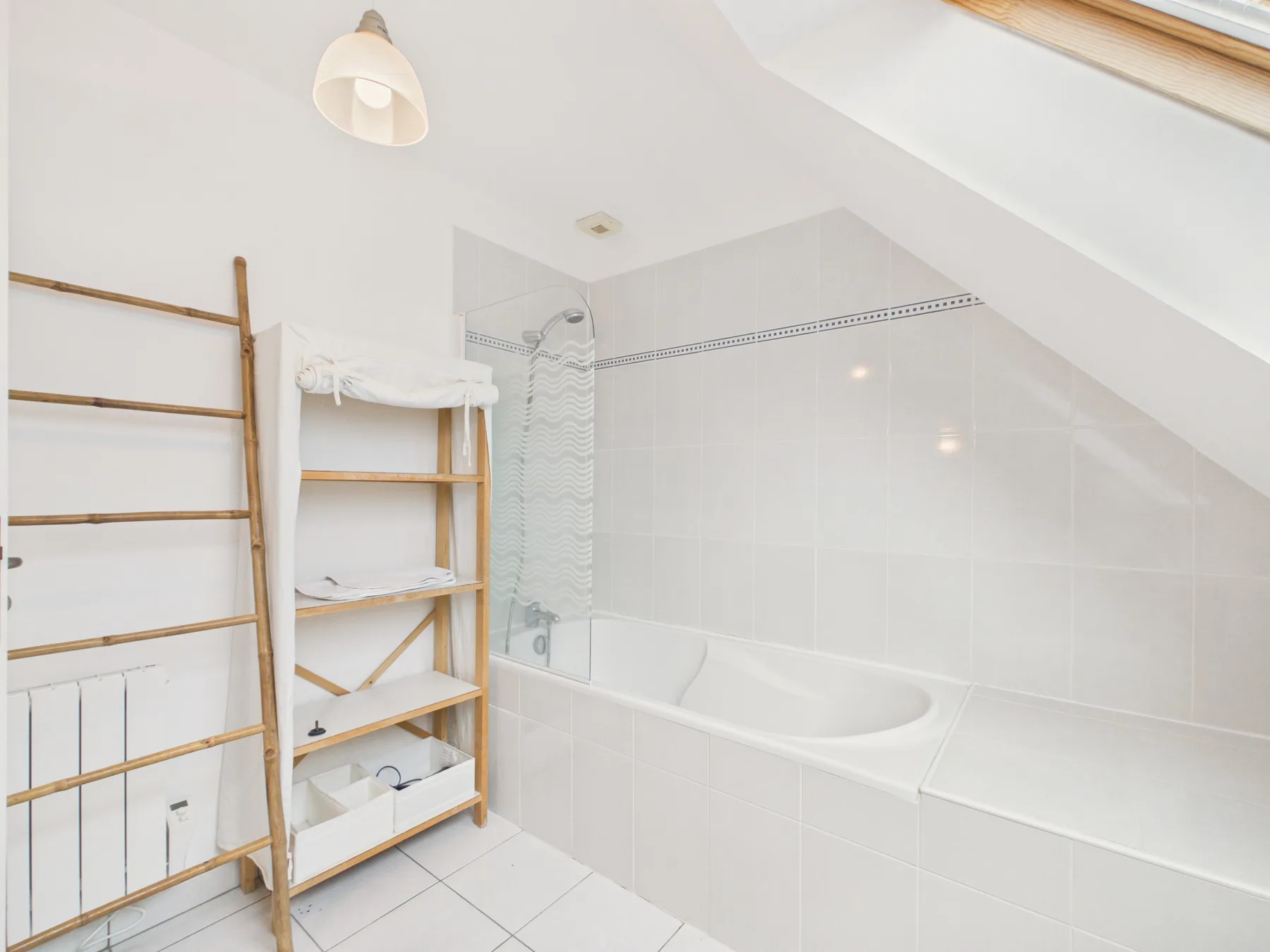 A tiled bathroom with a bathtub and open wooden shelving.