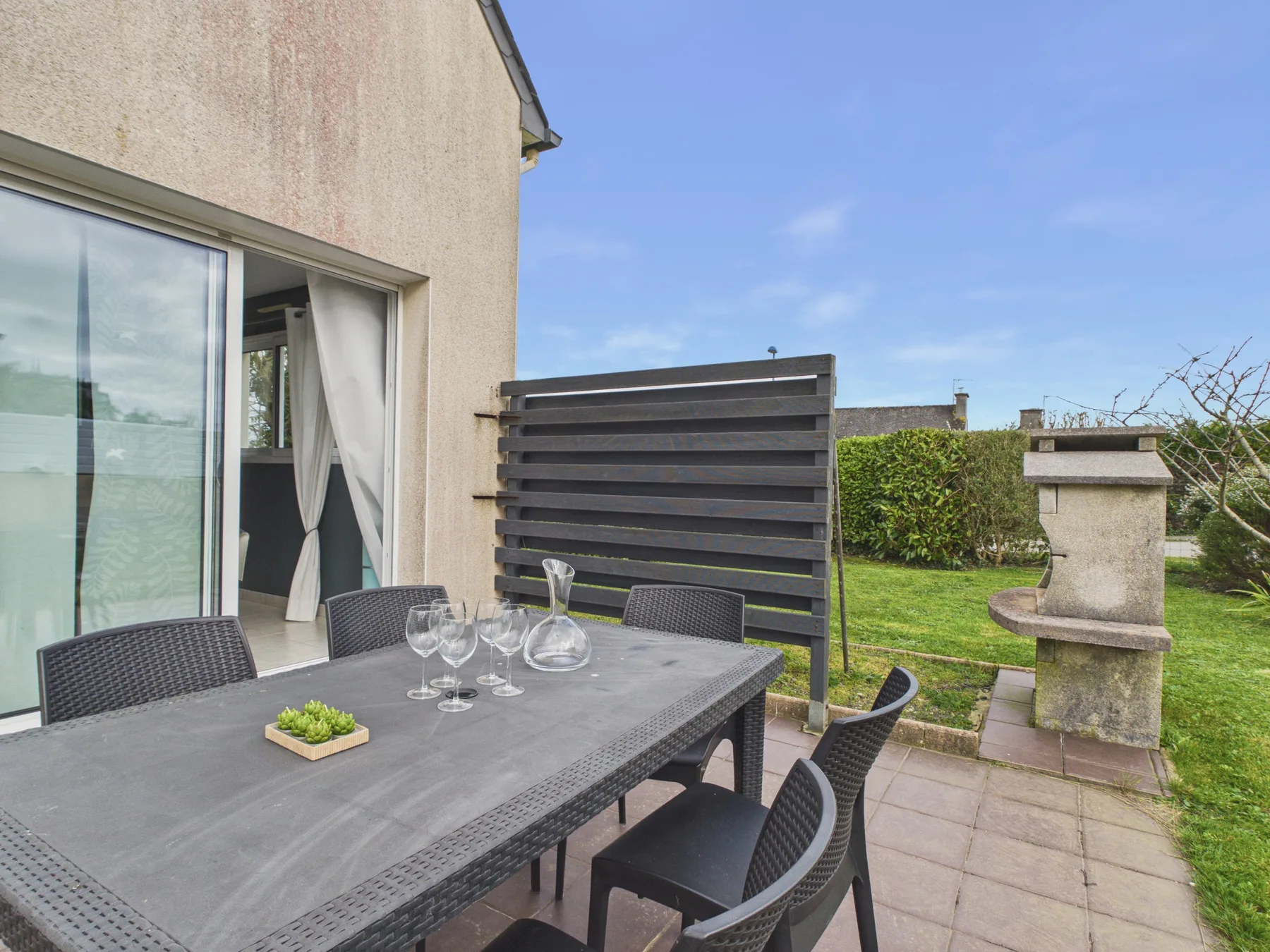 Outdoor dining area with a table and seating beside the house.