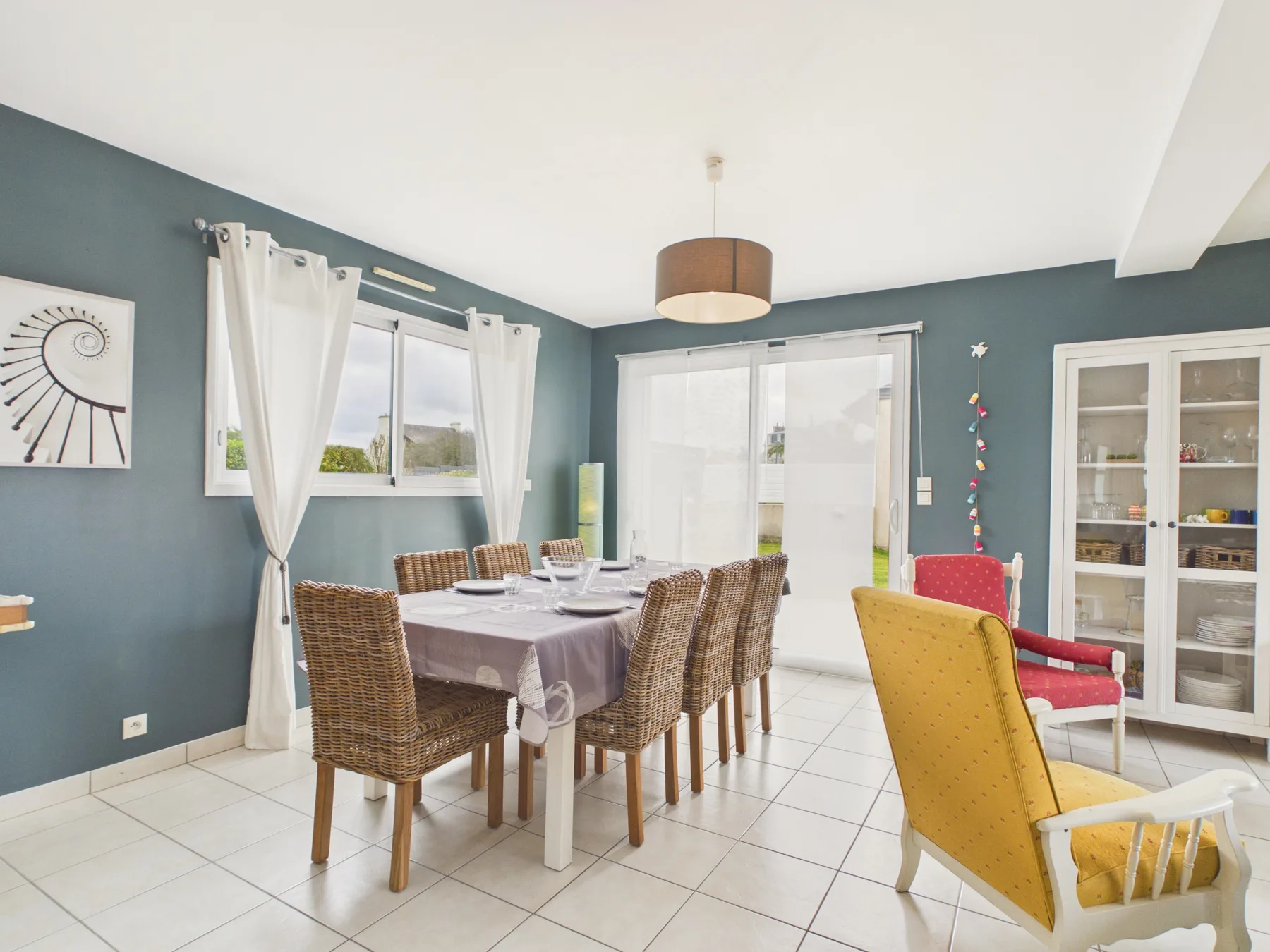 A dining area with a table and woven seating beside a bright window.