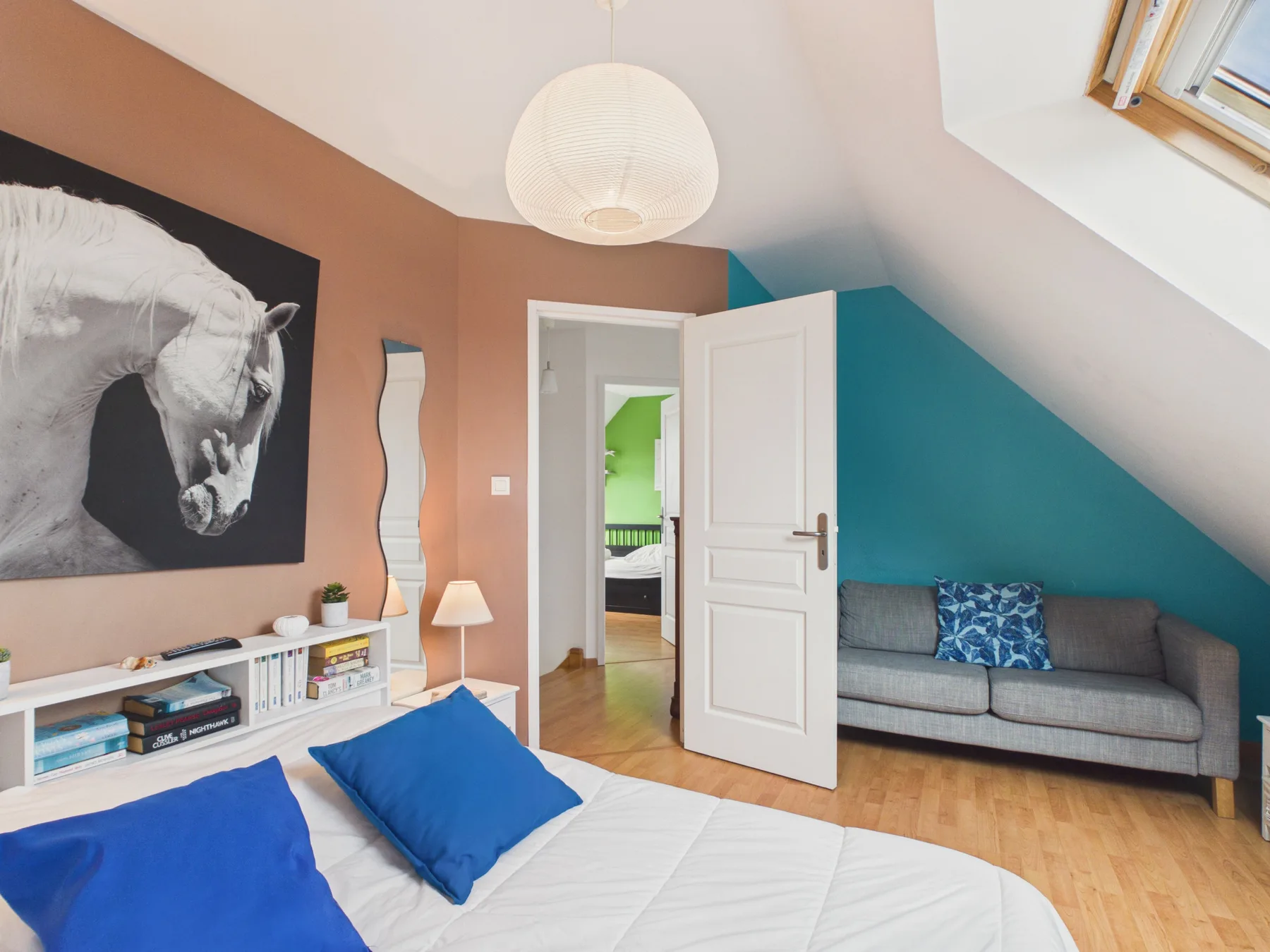 Bedroom with a bed and gray seating beneath a sloped ceiling.