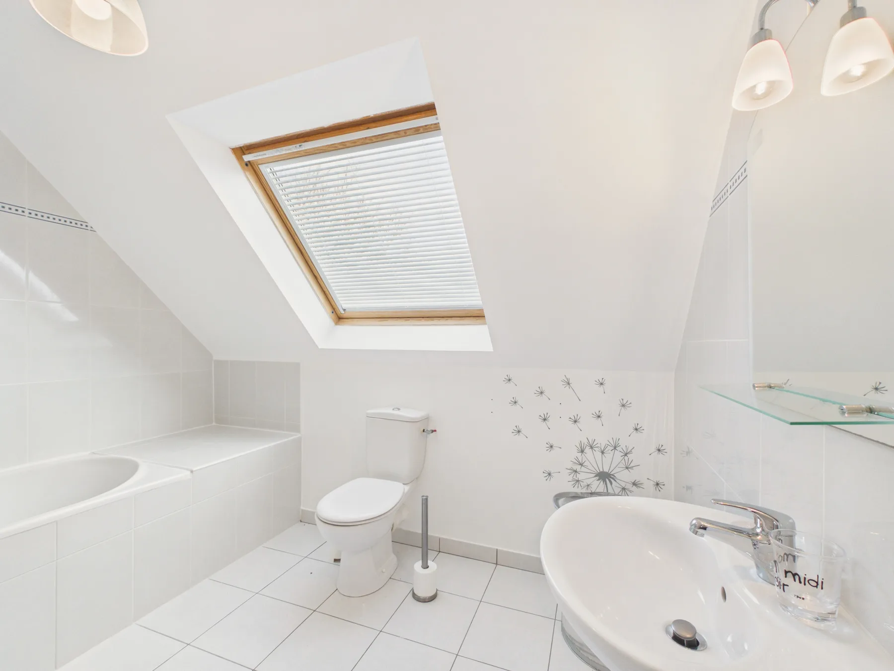 A bright bathroom with a bathtub, toilet, and skylight.