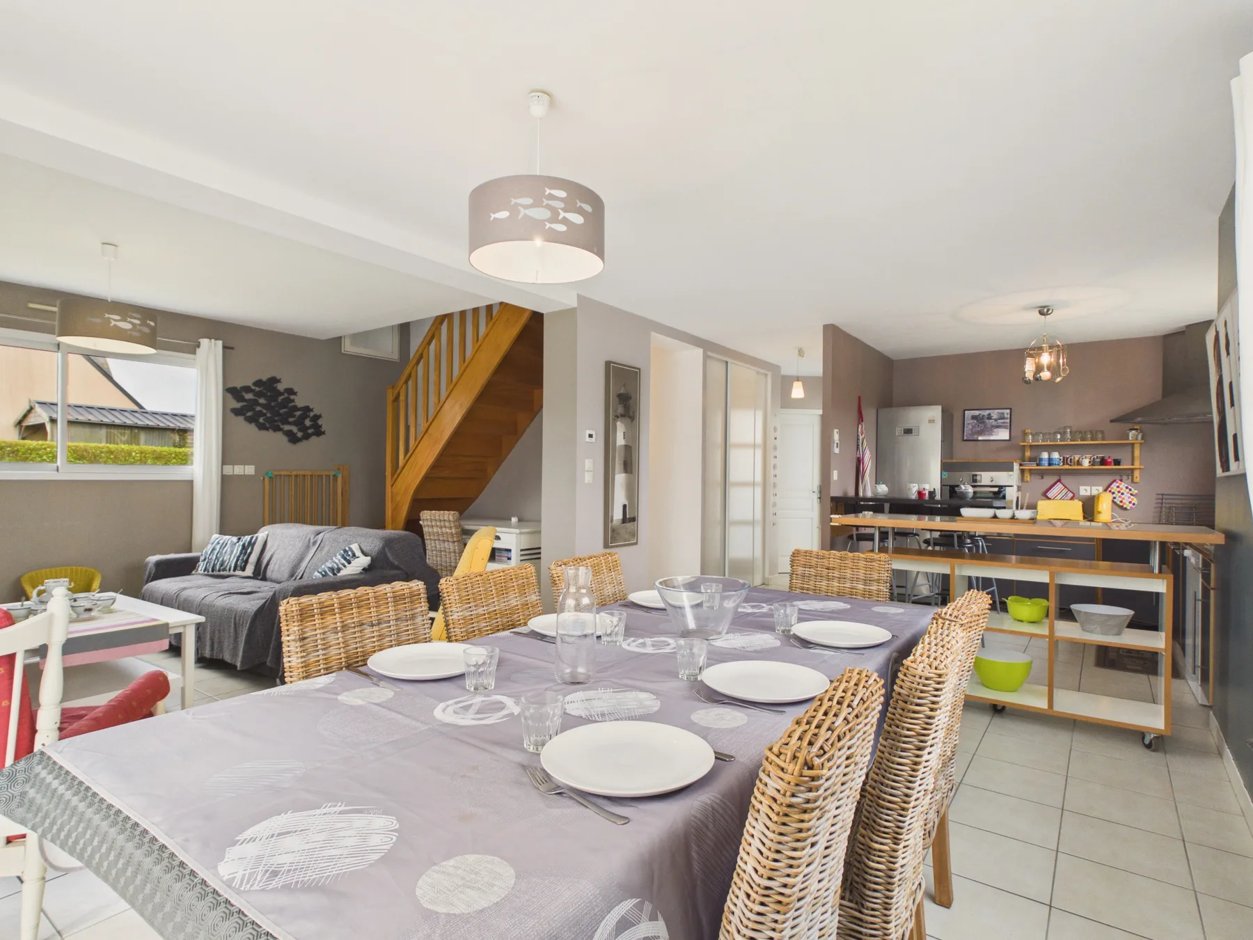 Dining area with a long table beside the living room and open kitchen.