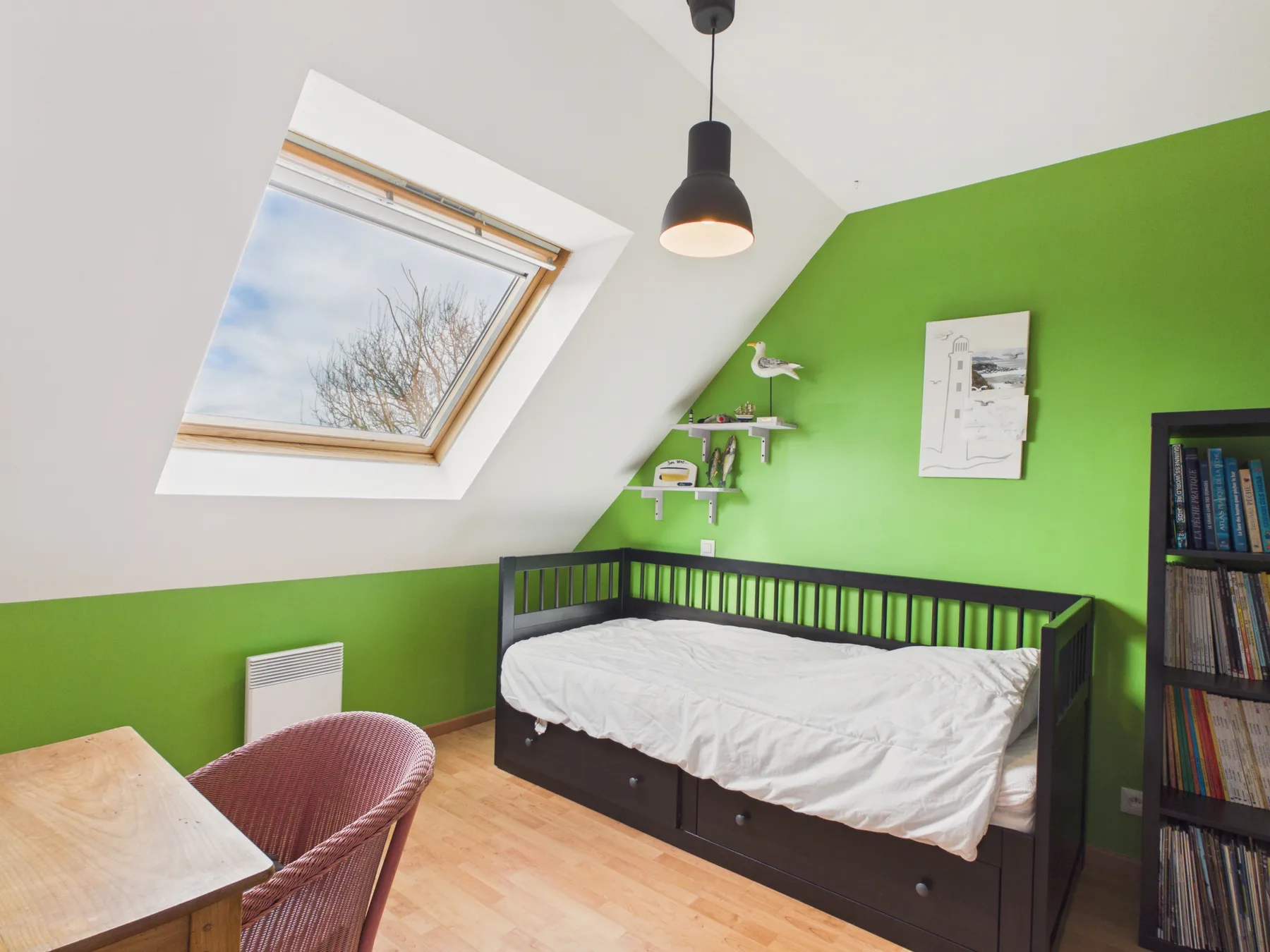A bedroom with a black daybed beneath a bright green wall.