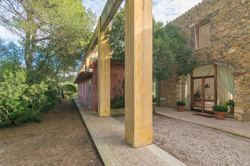 Un edificio de piedra da a un patio de grava junto a un pasillo cubierto.