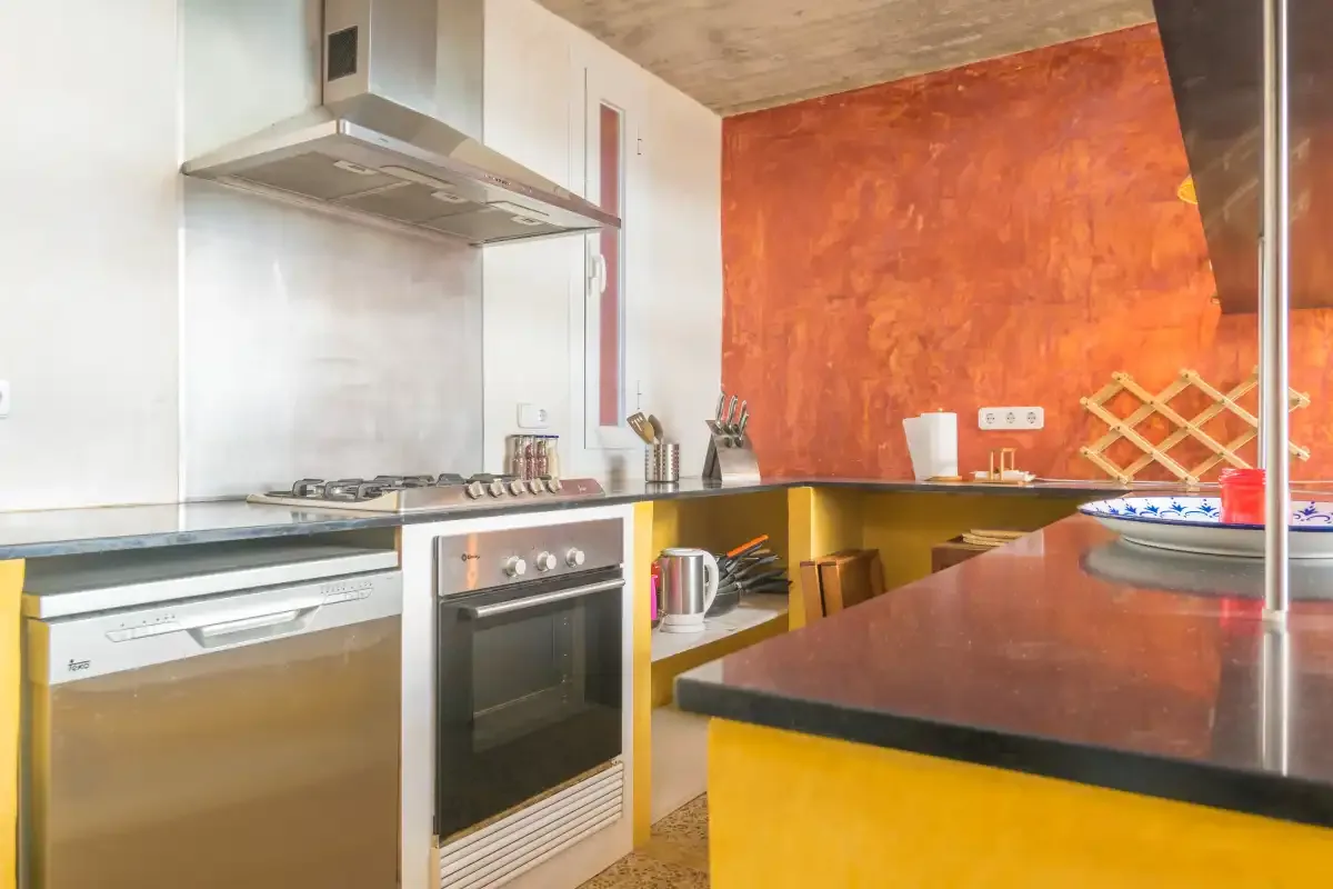 Una cocina moderna con una cocina de acero inoxidable y una amplia encimera oscura.