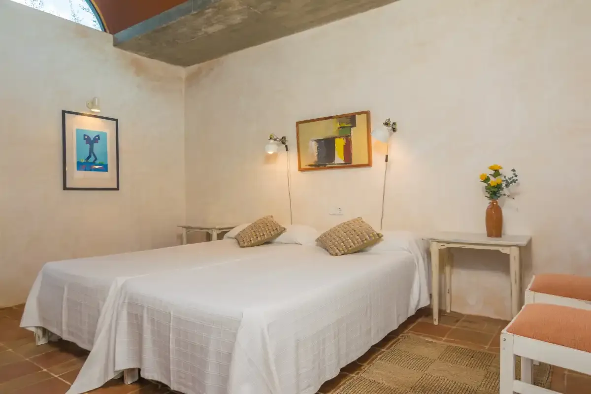Dormitorio con una cama bien tendida y cuadros en las paredes.